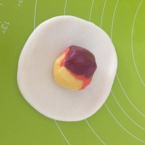 取一个水油皮压扁擀成饺子形状，包入一个油酥