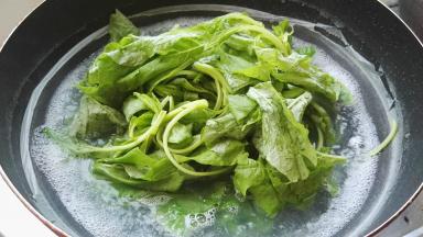 锅转大火，把苋菜放煮面水中，用筷子抄散。