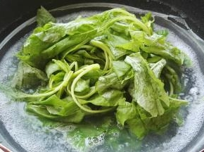 锅转大火，把苋菜放煮面水中，用筷子抄散。