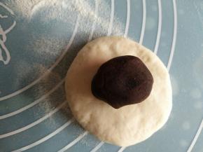 取一个面团按压排气；放上一份豆沙馅