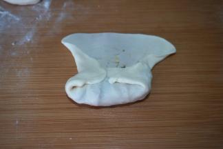 将底边向上折起，盖住馅料，向将两侧的面皮向内折