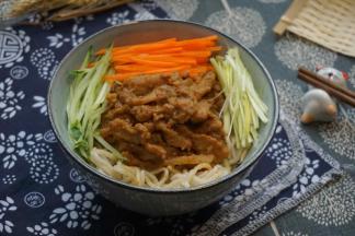 面条捞出装碗，放入肉丝、胡萝卜丝、黄瓜丝、蒜丝