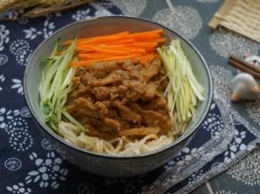 面条捞出装碗，放入肉丝、胡萝卜丝、黄瓜丝、蒜丝