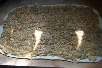 将一片的馅料均匀铺抹在面片上，用刀在上下长边处均匀切两刀，使整个面片形成九宫格形状或者假想成是一个“井”字