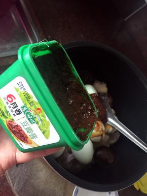 然后将猪脚放入锅中加入葱伴侣6月香黄豆酱、盐、白砂糖、生抽、老抽、葱姜料酒、香料