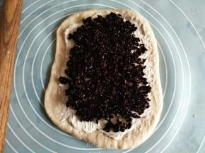 取一个面团擀成面片；涂抹奶酪馅；把蒸熟的黑米撒上去