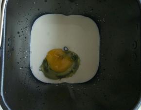 先把130克纯牛奶和1个全蛋加入面包机，一般用机器揉面最好先加水性的材料，避免面粉溢出。