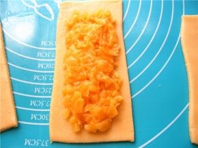 在一张派皮上放上菠萝馅，边沿留出0.5cm；在留出的边缘上刷蛋液；