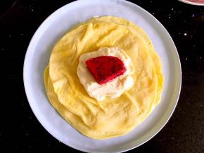 一张饼皮放上一勺奶油再取一块火龙果放在奶油上。