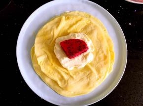 一张饼皮放上一勺奶油再取一块火龙果放在奶油上。