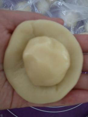 取一份水油皮擀圆，包入一份油酥，收口要捏紧