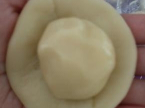 取一份水油皮擀圆，包入一份油酥，收口要捏紧