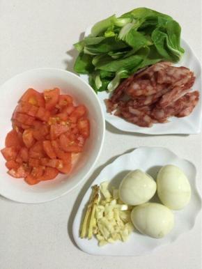 
准备材料：西红柿划十字刀，用开水烫一下，剥皮切成小丁，青菜洗净，香肠切成薄片，鸡蛋煮熟后剥皮备用，蒜瓣剁碎，生姜切成丝备用！

