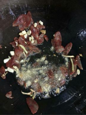 锅烧热倒入适量的油，放入蒜瓣，生姜炒香后，下入香肠翻炒片刻！

