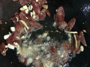 锅烧热倒入适量的油，放入蒜瓣，生姜炒香后，下入香肠翻炒片刻！

