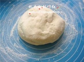 余下的高筋面粉20g洒在案板上，将面团放在上面