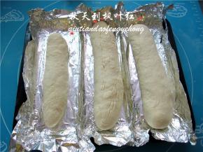 在烤盘里放上锡纸折叠起来作为墙壁，将整形好的法棍面包坯放入；