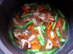 将炒制的鸡腿蔬菜倒入三分之二，按下煲饭键开始煲饭。