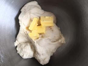 分次加入软化的黄油，继续厨师机揉面