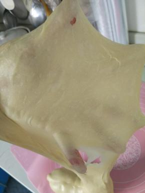 把除了黄油之外的材料全部混合，用手揉面20分钟，直到光滑有弹性，加入软化好的液态黄油继续揉，这里的面团会惨不忍睹，有点粘稠，不要放弃，继续，坚持揉到手套膜，天气热，手揉面虽然辛苦，但做出来的土司绝对比面包机揉的面团好吃的多（自认为哈哈）