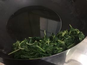 6. 把煮好的麻叶捞在锅壁上控干水，为了下一个步骤缩短时间，用筷子在麻叶上压一压把水份压出来，把剩余的水倒掉