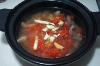 将西红柿倒入牛肉砂锅内，再加够足量的热水，将大蒜瓣、姜片同入锅中；我用的电炖锅，选择“红烧牛羊”的程序，时间设为2个半小时