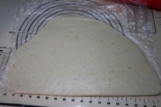 剪开一个保鲜袋，效果比保鲜膜要好，将土豆泥团放在保鲜袋上，对折一下，擀成厚约8毫米左右的片