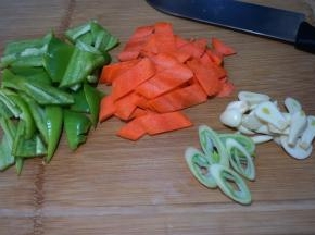 尖椒去蒂去籽切块，胡萝卜用半根切象眼片，大葱斜切成丝，大蒜切片
