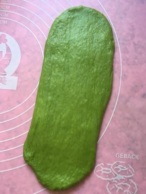 松弛好的面团用擀面杖擀开，从上至下卷起