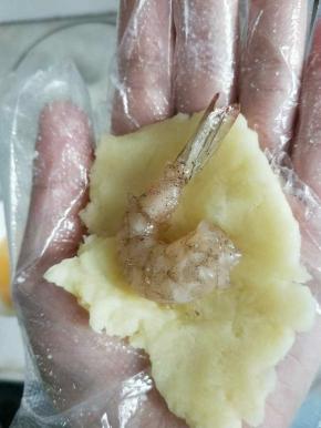 取少许土豆泥包入一只腌好的虾，团成球，虾尾露在外面。