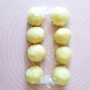 3..将发酵好的面团从容器中轻轻托出（注意不是扯出），按压排气后均分成8个小面团。把8个小面团依次滚圆后盖上保鲜膜松弛20分钟左右。