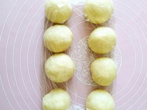 3..将发酵好的面团从容器中轻轻托出（注意不是扯出），按压排气后均分成8个小面团。把8个小面团依次滚圆后盖上保鲜膜松弛20分钟左右。