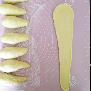 7.取一个松弛好的水滴面团将其擀成长三角，擀的时候可以用手沾少许干粉轻拉住末端，只是擀长不要擀宽。
