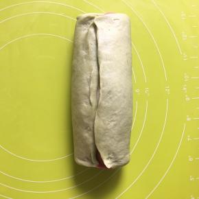 把绿色和原色面团从红面团的中间收口，捏紧