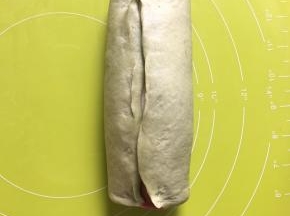 把绿色和原色面团从红面团的中间收口，捏紧