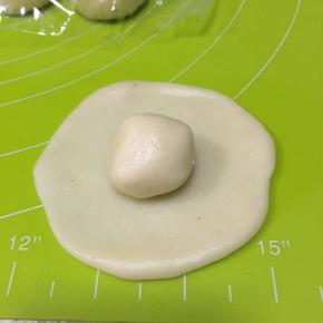 取一个水油皮面团压扁擀成圆状，包入一个油酥