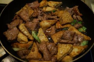 将豆腐片入锅中翻拌均匀，撒少许盐、倒少许酱油、少许热水，咕嘟一分钟，让汤能吸进豆腐中