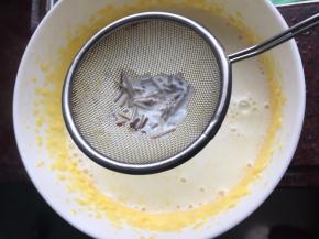 然后将牛奶通过网筛倒入蛋黄中，滤去香草籽