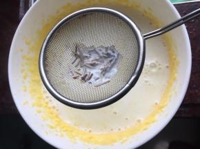 然后将牛奶通过网筛倒入蛋黄中，滤去香草籽