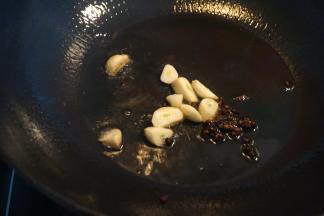 先将一撮花椒煸炒出香味，再将蒜块入锅煸微黄