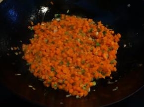 炒锅中倒少许油，葱花煸炒出香味后 ，将胡萝卜丁入锅中煸炒变色