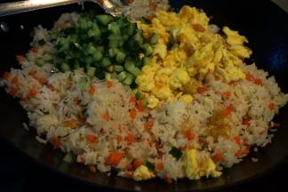 当米饭粒粒分明时，将鸡蛋块、黄瓜丁倒入锅中翻炒均匀