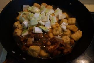 红烧肉取适量，入锅中，将白菜帮子也入锅中，倒入适量的热水和酱油，盖盖，中火煮开