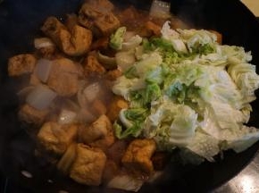 白菜帮子熟了，豆泡吸汁入味了，将白菜叶入锅中，再撒适量盐，菜叶变软就可关火出锅