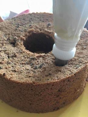 如图所示，将裱花嘴插入孔中，将提拉米苏酱挤入蛋糕中。可以明显观察到蛋糕糕体因为受到夹心的挤压而膨胀。