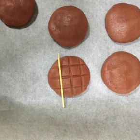 稍微按压一下成小圆饼，用牙签横竖各压三下，形成菠萝包样子的纹路