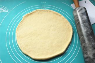 面团擀成薄片，比披萨盘略大。