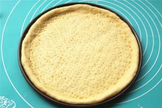 面胚放入披萨盘，整理一下边缘，用叉子叉出小孔，避免烤的时候鼓泡。