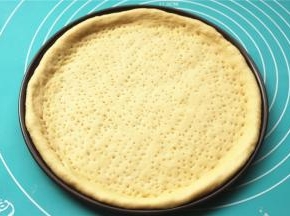 面胚放入披萨盘，整理一下边缘，用叉子叉出小孔，避免烤的时候鼓泡。