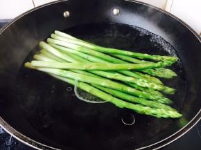 锅里放水，水开了后，放入1小勺盐、2滴炒菜油，放入芦笋，大火煮开，煮约2分钟左右，捞出来过凉水，沥干水分备用。